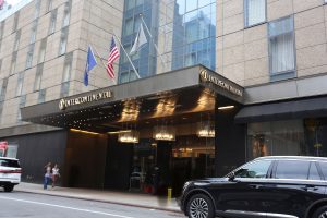 InterContinental New York Times Square, a gay-friendly hotel. Entrance view with flags, lighting, and a car parked nearby. Great for gay travel.