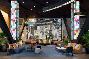 M Social Times Square lobby. Gay-friendly hotel interior with colorful columns, NYC mural art, and modern seating for guests.