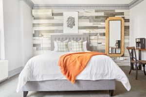 Sonder The Wellesley hotel room. Gay-friendly travel lodging with bed, orange throw, and decor. Modern design at this top gay travel destination.