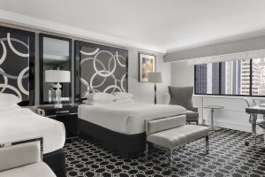 The Muse New York, a gay-friendly hotel. Room with two beds, patterned headboards, city view. Stylish lodging for gay travelers.
