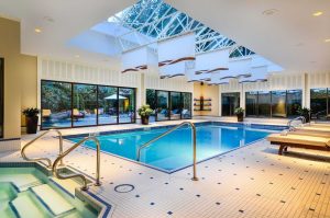 Indoor pool at The Sutton Place Hotel Vancouver, a gay-friendly hotel. Bright, with skylight, lounge chairs, and jacuzzi. Relaxing vacation.