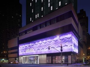 YOTEL Times Square, a gay-friendly hotel in New York. Exterior view at night with purple honeycomb lighting. Great for gay travelers' stay.