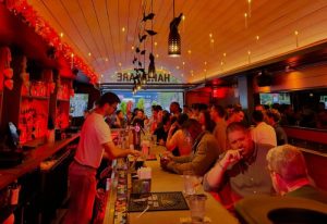 Hardware Bar in New York. A busy gay bar scene with a bartender serving drinks and patrons enjoying themselves in a warm, inviting space.
