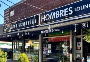 Hombres Lounge in New York. Exterior of the gay-friendly restaurant, Churrasqueira Hombres Lounge, with string lights and rainbow flag.
