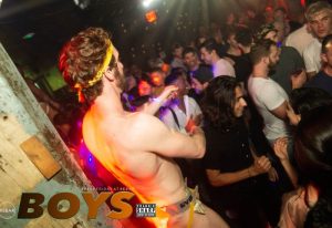 Crowded gay dance party at Rebar Chelsea in New York. Shirtless man in underwear dances. Gay nightlife travel advice.