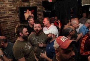 Rockbar NYC crowd scene. Gay bar in New York City, brick wall, TV screen, men drinking, socializing, and enjoying the gay nightlife scene.