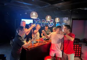 Gay men toasting at Tapas Waikiki, a gay-friendly drink place in Honolulu. Bar scene with drinks, friends, and a fun atmosphere.