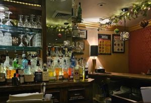 The Townhouse Bar in New York: Bottles of liquor line the bar's surface, with glassware above. Holiday decorations add festive cheer. Gay bar.