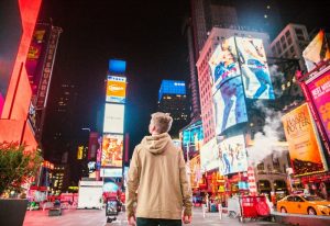 Gay New York Travel: Man gazes at Times Square's bright lights at night. This year's travel advice for gay men visiting NYC.