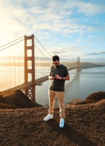 Gay San Francisco Travel Guide: Man with phone overlooking Golden Gate Bridge. Perfect spot for gay travel in San Francisco.