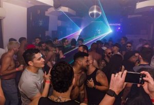 Inside True Colors Bar, New York. Gay men socialize under disco ball and laser lights. Nightlife, travel advice for gay men.