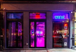 VERS venue in New York. Night view of the gay bar entrance, illuminated with neon lights. Gay travel advice in NYC.