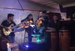 Live music at Garbo Piano Bar, a gay bar in Puerto Vallarta. Four musicians play bass, guitar, congas, and sing. Nightlife scene.