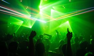 Crowd at a Benidorm gay dance club, bathed in green laser lights. Nightlife scene with people dancing and enjoying the music.