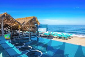 Almar Resort, a luxury LGBT beach front hotel, adults only. View of the pool, beach, ocean, and thatched roof bar. Gay-friendly hotel.