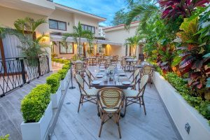 Casa Nicole Boutique Hotel's outdoor dining area. This gay-friendly hotel offers a relaxing atmosphere with lush greenery and elegant tables.