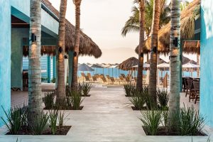 Delta Hotels by Marriott Riviera Nayarit All-Inclusive, a gay-friendly hotel. Beach view framed by palm trees & thatched roofs.