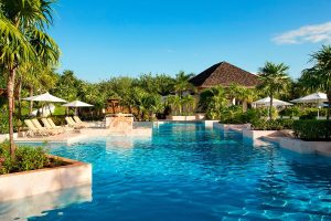 Fairmont Mayakoba's pool. This gay-friendly hotel offers luxury, sun loungers, umbrellas, and lush greenery. A perfect gay travel destination.