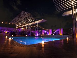 Galeria Plaza Reforma gay-friendly hotel pool at night. Rooftop pool with lights, tables, and chairs. A great place for gay men to relax and enjoy.