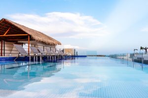 Hotel 52, a gay-friendly hotel. Infinity pool view with lounge chairs under a thatched roof. Perfect for gay travel and relaxation.