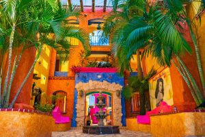 Hotel Hacienda Maria Bonita, a gay-friendly hotel. Colorful courtyard with fountain, palm trees, and Mexican architecture. Ideal for gay travel.