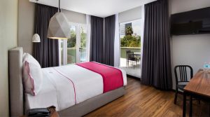 Hotel MX mas reforma gay-friendly room. A bed with a pink runner, balcony, desk, and geometric lights. Perfect for gay travel.