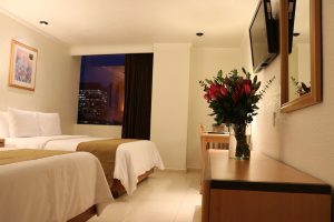 Hotel PF gay-friendly room with two beds, night cityscape view, flowers, and TV. A comfortable stay for gay travelers.