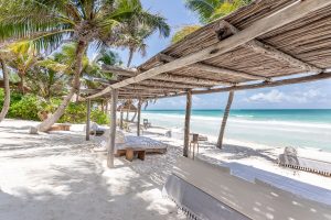 La Valise Tulum gay-friendly hotel beach view. Thatched roof, palm trees, and ocean scene. Ideal for gay men's travel in Tulum, Mexico.