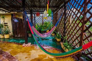 Maison Tulum gay-friendly hotel: Hammocks hang over a shallow pool in a covered patio. Tropical plants add to the relaxing vibe.