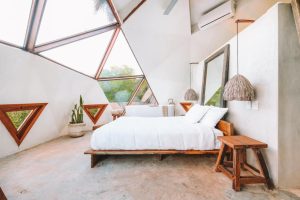 Mamasan Treehouses & Cabins bedroom. Gay-friendly hotel room with triangle windows, white linens, and modern design. A relaxing getaway.