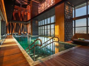 Indoor pool with city views at the gay-friendly Sofitel Mexico City Reforma hotel. Wood floors, lounge chairs, and modern design.