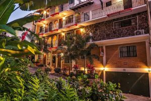 ZonaZ Boutique Hotel, a gay-friendly hotel. Exterior view of the hotel with plants, balconies, and warm lighting. Gay travel advice.