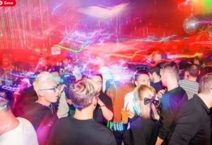 Shanghai gay nightlife: Crowded gay club scene with disco ball and colorful lights. Men socializing, enjoying drinks, and dancing.