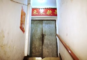 Stairs leading to Lai Lai Dance Hall, a gay nightlife spot. A red sign with Chinese characters above a metal door. Gay travel destination.