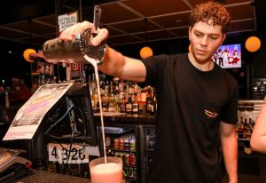 Bartender pours a pink cocktail at Newtown Hotel, Sydney. Gay travel advice: enjoy the vibrant nightlife and friendly atmosphere.