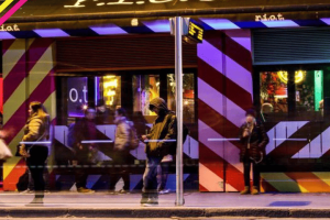 Riot Gay Bar, Dublin. Night scene with people outside the bar, which has a red and white striped facade. Gay travel advice.