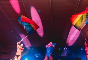 Melbourne Rock City Party: Drag queen and dancers with rainbow flags on stage, celebrating gay pride. Gay travel in Australia.