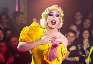 Drag queen in Sydney's Universal nightclub, a popular gay venue. She wears a yellow dress, blonde wig, & heavy makeup. Nightlife.