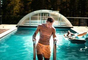 Gay Tulum: Man exiting pool at a gay-friendly hotel. Another man relaxes on a float. John Fornander photo. Gay travel advice.