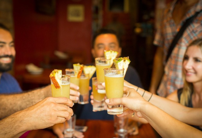 Gay travelers enjoying a tequila toast in Puerto Vallarta. Pineapple garnishes the drinks on this mixology and taco tour.