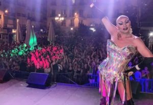 Drag queen on stage at a gay club in Madrid. Crowd with hands up, lights, and energy. Gay travel nightlife scene.