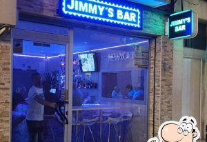 Jimmy's Bar in Benidorm. Exterior view of the gay bar with blue neon signage. A popular gay travel destination for men.