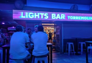 Lights Bar, a gay bar in Torremolinos, Spain. Men sit at tables under blue lights. A popular nightlife spot for gay travelers.