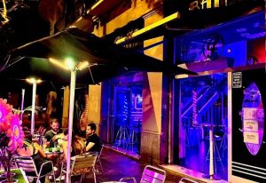 Plata Cocktail Bar, a gay bar in Barcelona. People enjoy drinks outside this vibrant, neon-lit bar, a hot spot for gay men.