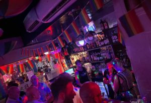 Inside Spirit Bar, a gay bar and party venue in Benidorm. Rainbow flags, disco balls, and people enjoying the vibrant atmosphere.