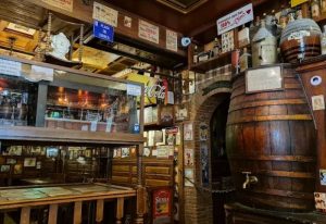 Interior of Taberna de Ángel Sierra, a gay bar in Madrid. Rustic decor, wooden barrels, vintage signs, and cozy atmosphere. Madrid gay travel.