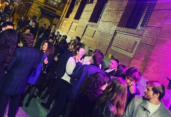 Nightlife at The Moon Tropical Gay Bar in Barcelona. A crowd of people socializing outside the bar, enjoying the vibrant atmosphere.