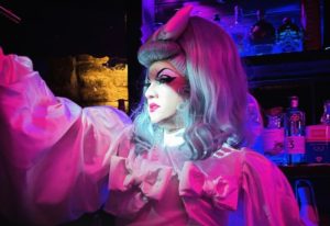 Drag queen at 101 Club Roma, a gay bar in Rome, Italy. Pink lighting highlights the performer's makeup and costume. Gay travel advice.