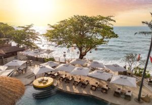 SAii Koh Samui Villas view. Beachfront resort with pool, umbrellas, and lounge chairs overlooking the ocean. Tropical gay travel destination.