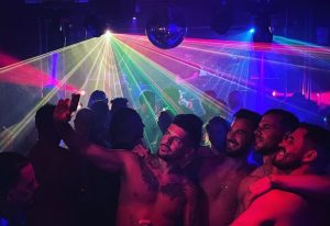 Torremolinos gay clubs nightlife: shirtless men take a selfie under laser lights and disco ball at a Torremolinos gay club. 700X480-1.jpg